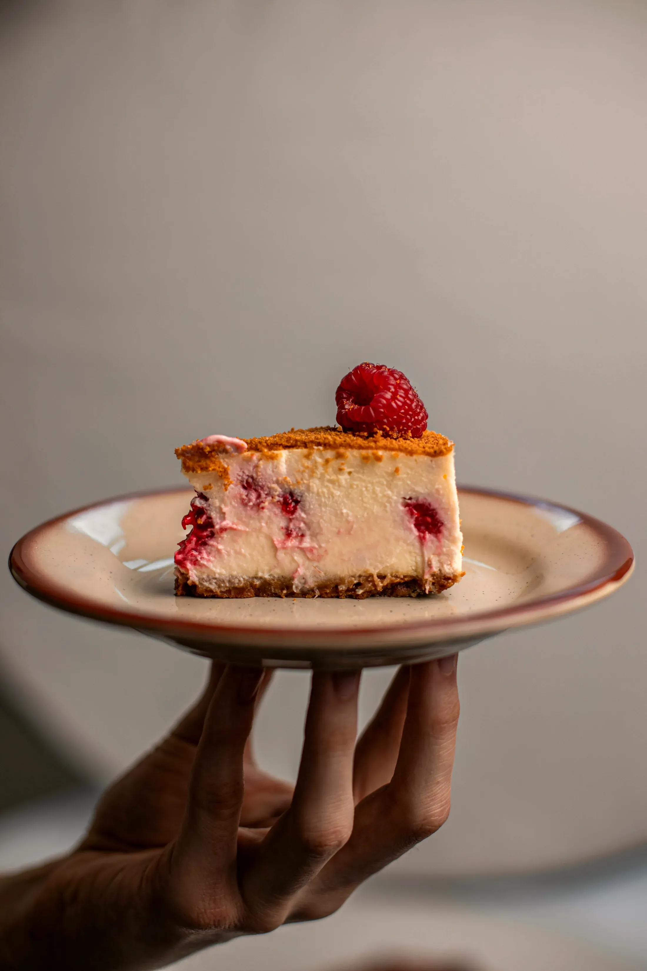La fetta di cheesecake ai lamponi sul piatto rosa