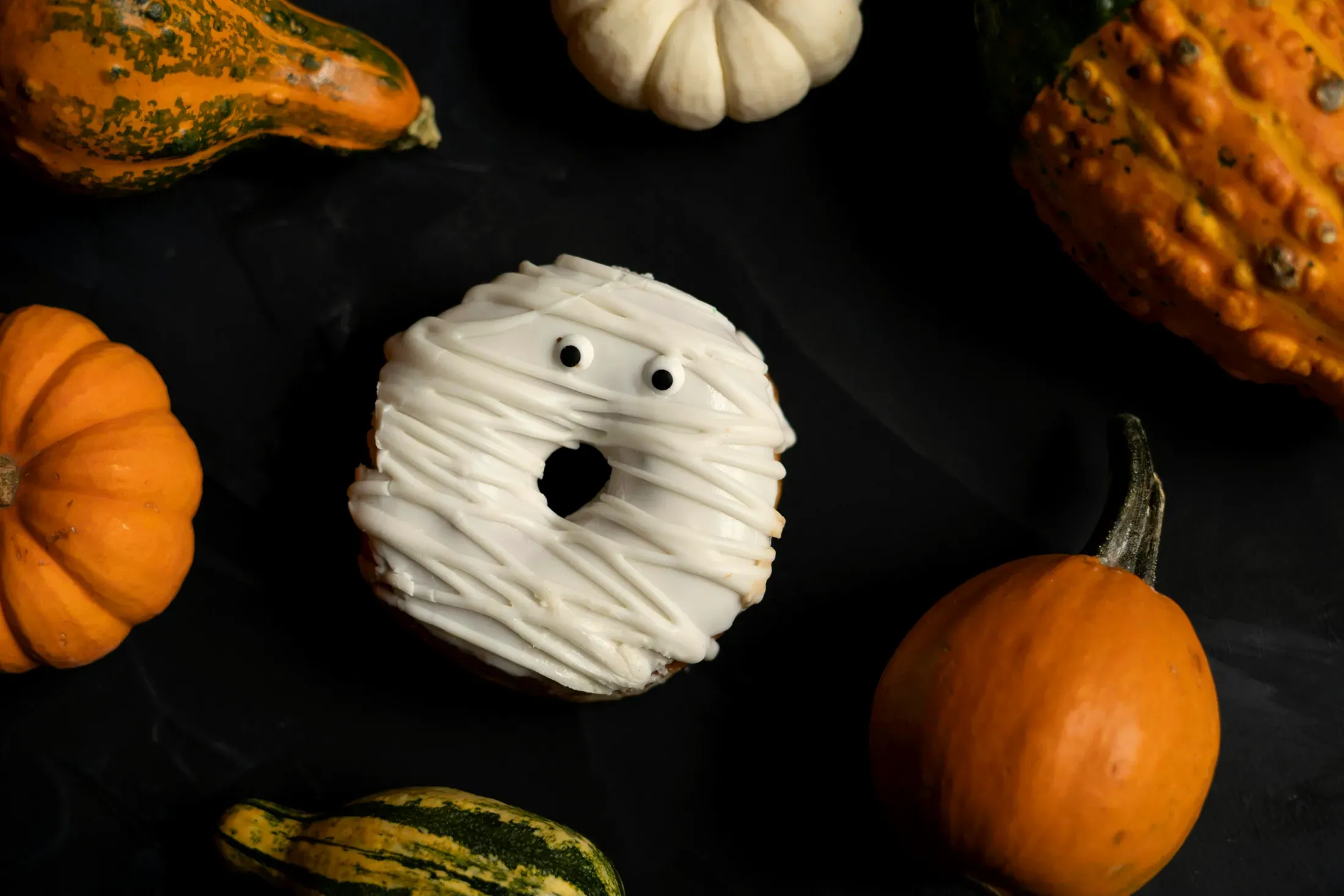 Il biscotto fasciato di glassa bianca, con gli occhi, accanto alla zucca bianca