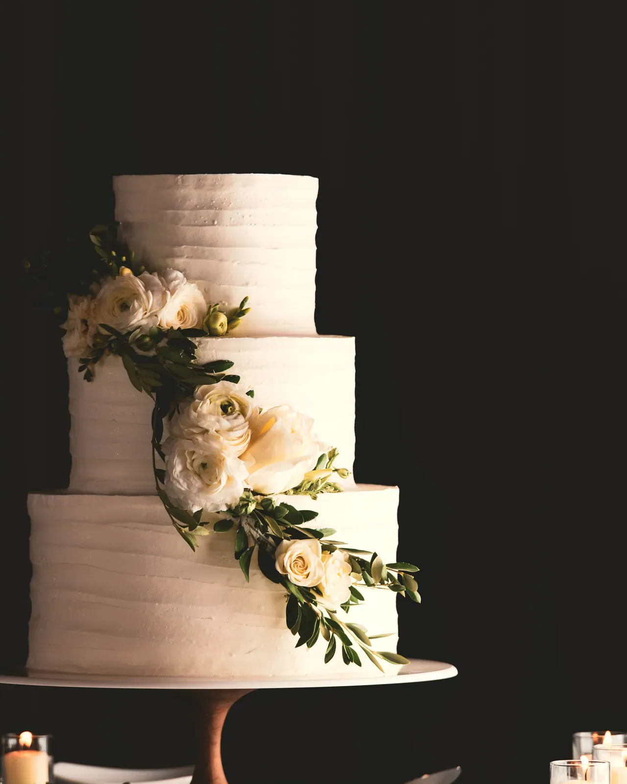 La torta nuziale a due piani con il verde, su fondo scuro