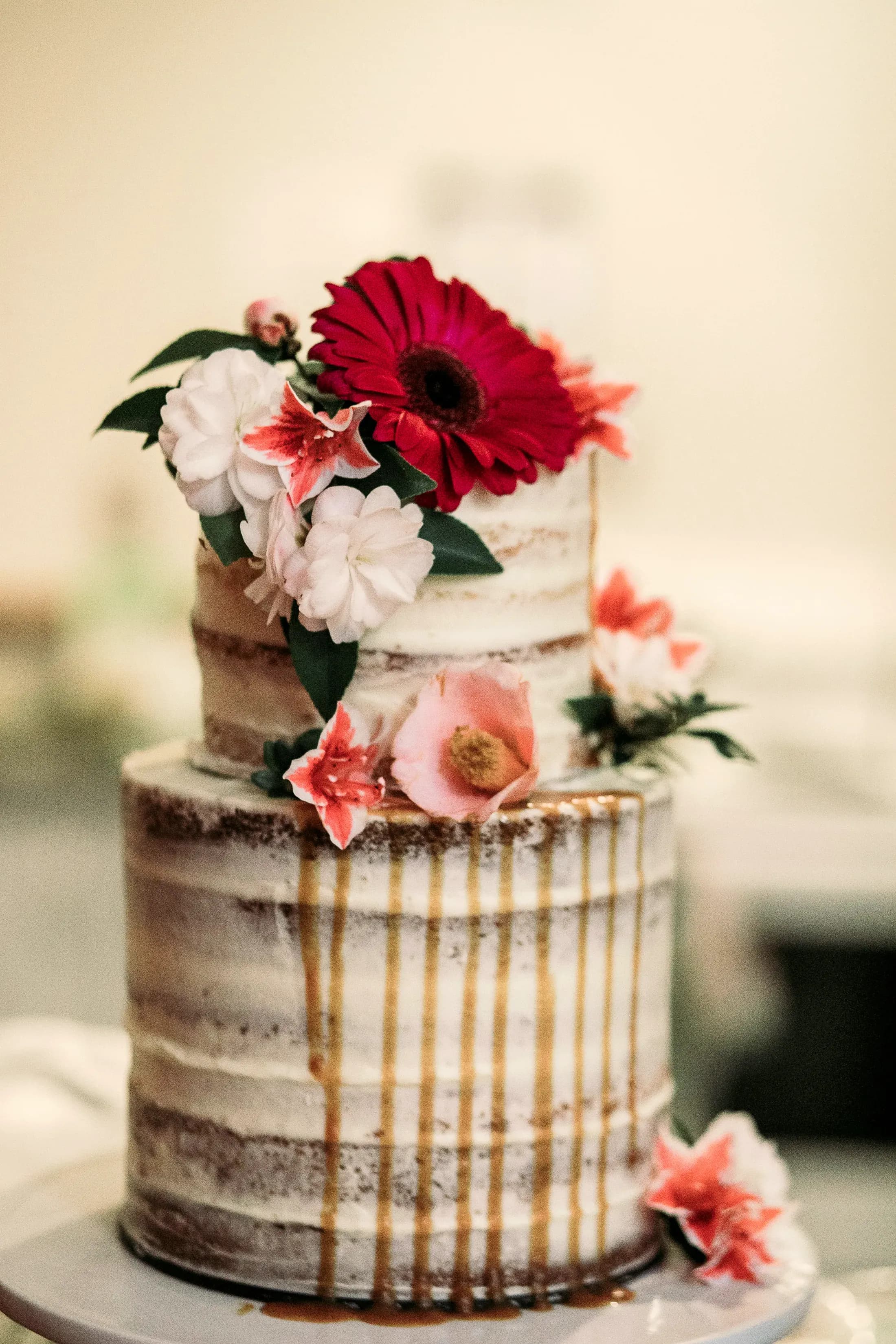 La torta nuziale seminuda con le rose rosse e i fiori