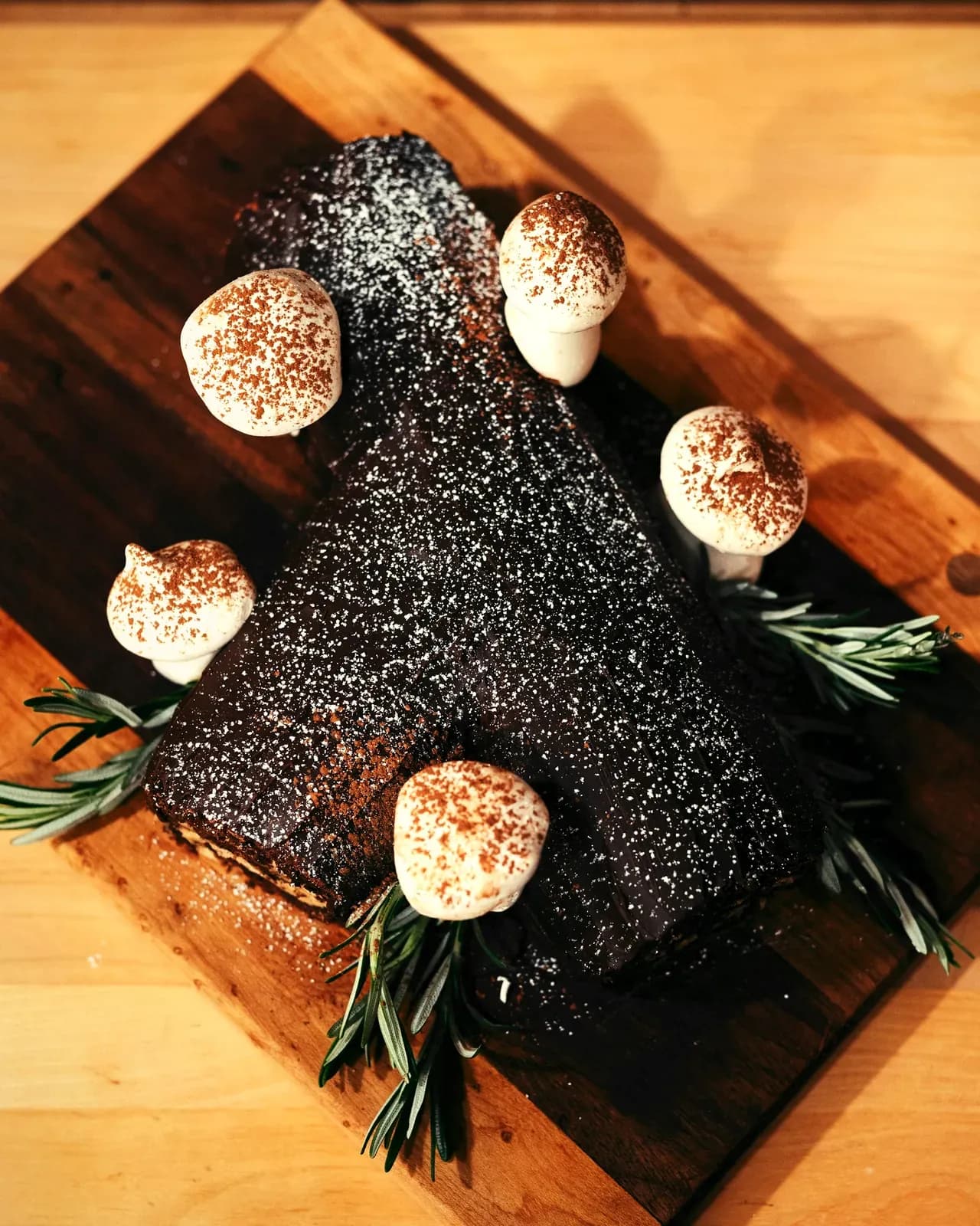 Il tronchetto di Natale al cacao con le meringhe e il rosmarino, sul legno