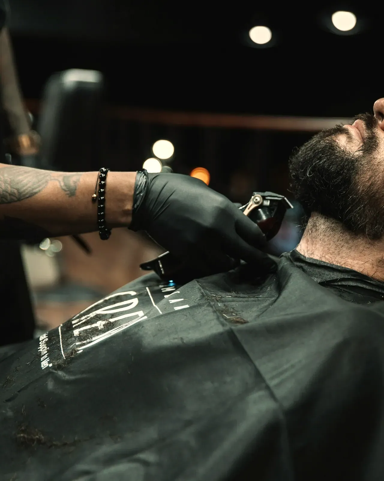 La barba regolata a macchinetta, i guanti neri, il cliente disteso