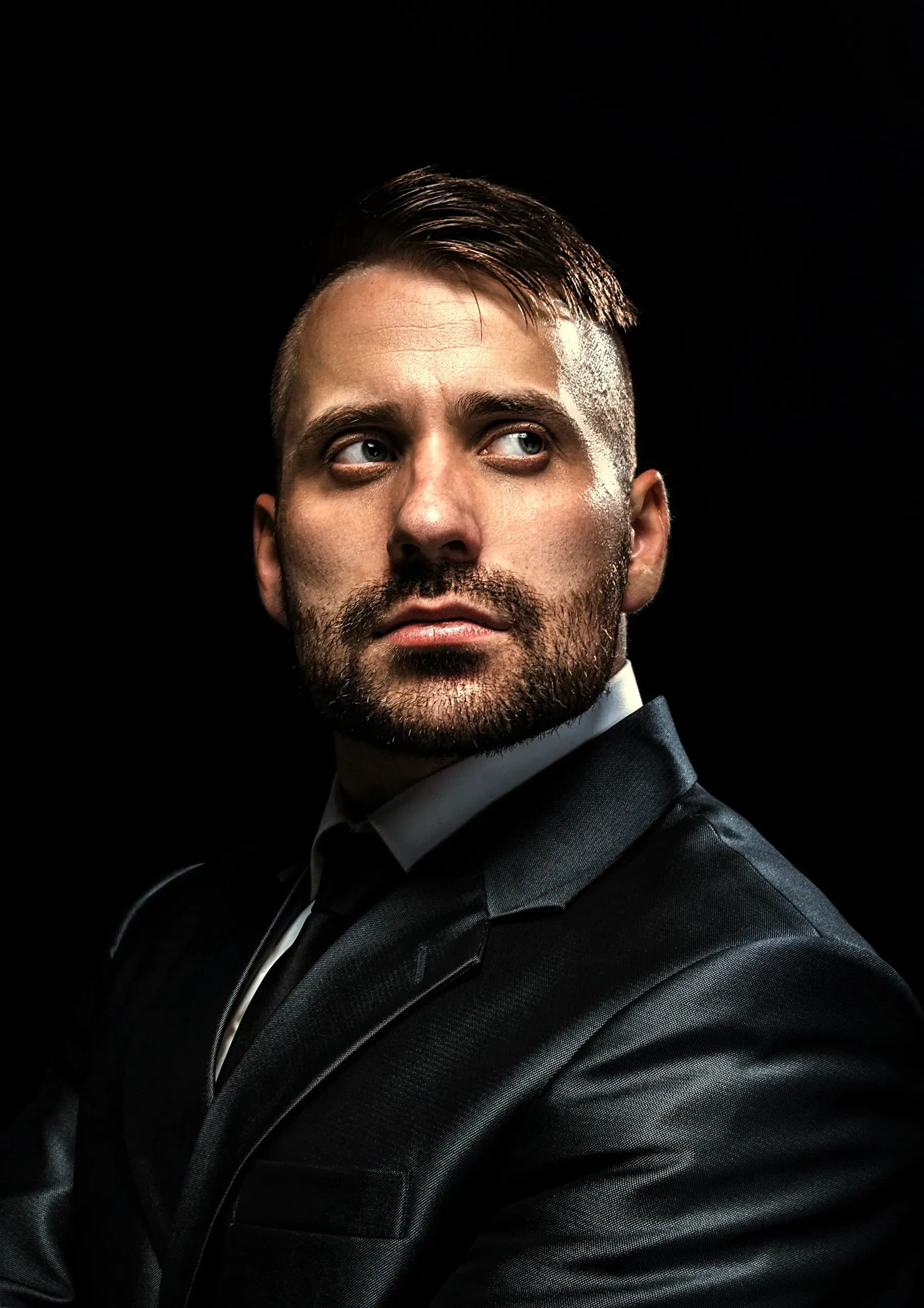 Taglio classico con la riga, barba corta, in abito scuro
