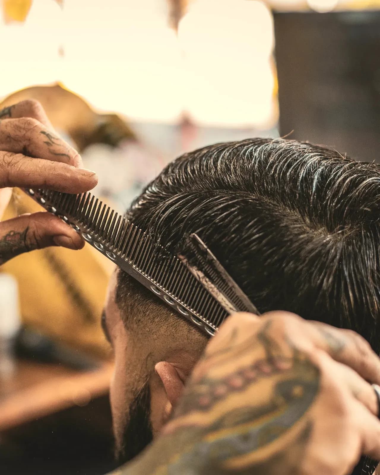Le mani del barber con forbici e pettine che rifiniscono il taglio