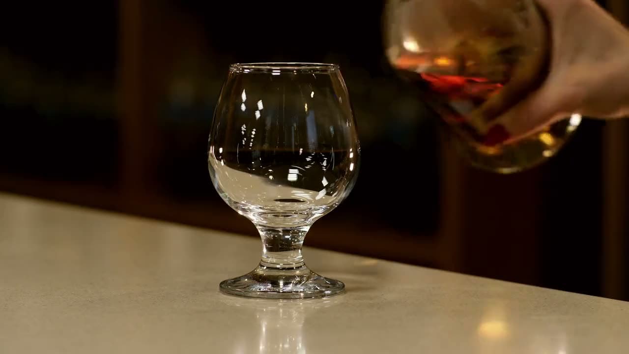 Il cognac versato nel bicchiere, sul banco