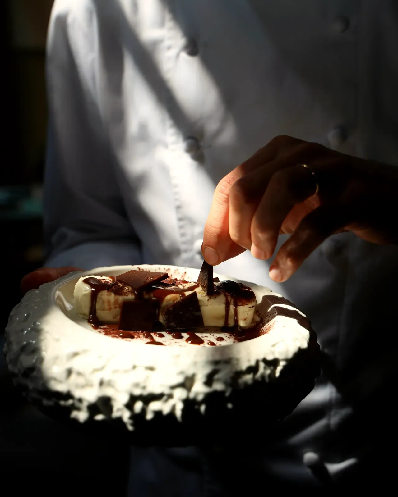 Le mani che finiscono la torta al cioccolato con il cacao