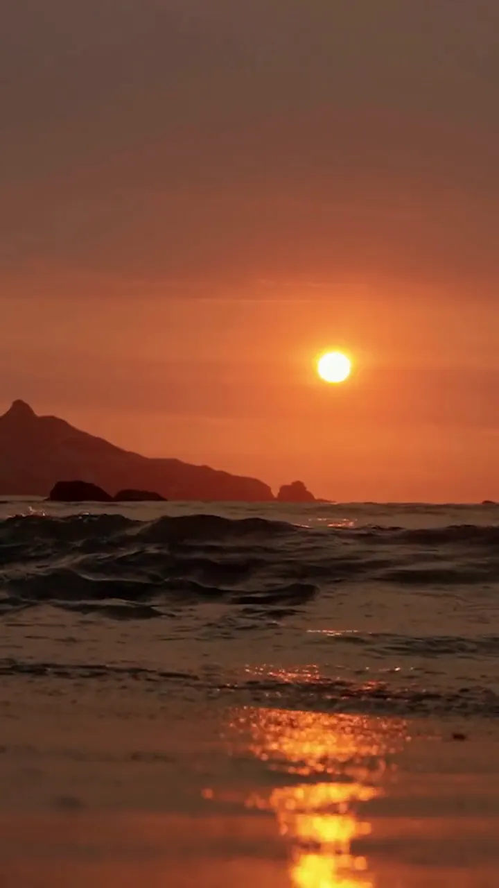 Il sole che tocca il mare, lo scoglio, la scia d'oro sull'acqua