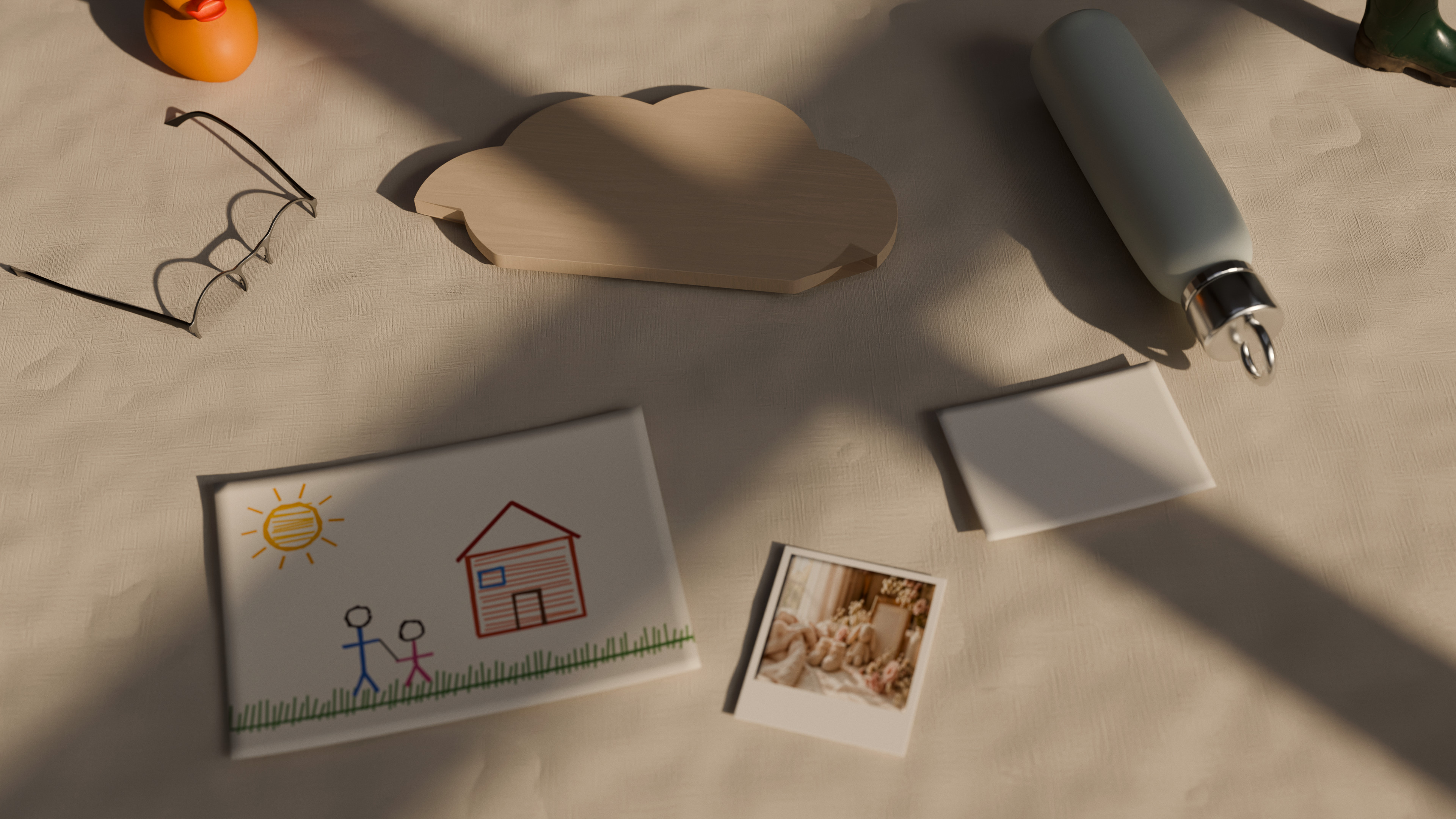 La targhetta di betulla col nome, un disegno a pastelli, una polaroid, la borraccia e il bigliettino su una tovaglia di lino