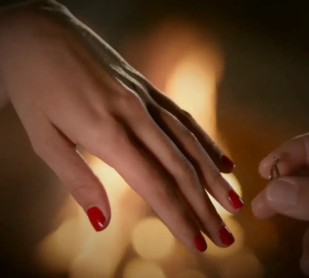 Una mano con lo smalto rosso davanti alle candele